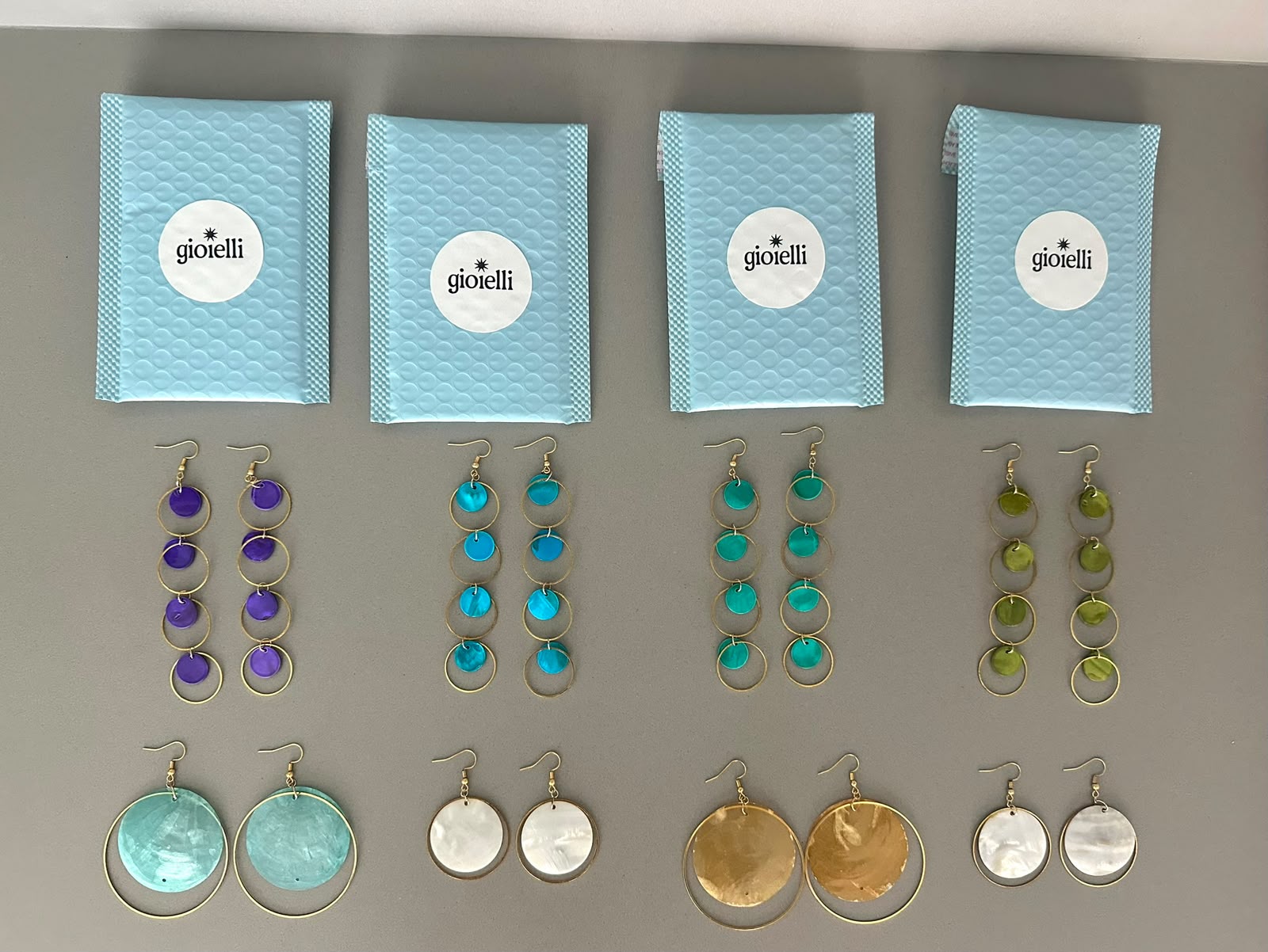 Overview of all Gioielli earrings — Lagoon in violet, turquoise, ocean blue and olive, plus Luna and Disco styles, with blue gioielli mailers
